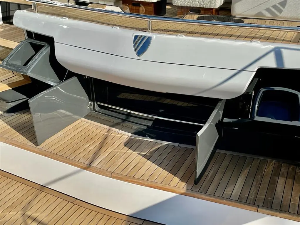 Sleek yacht with open storage compartments on the deck, showcasing a polished wooden surface and a modern design.